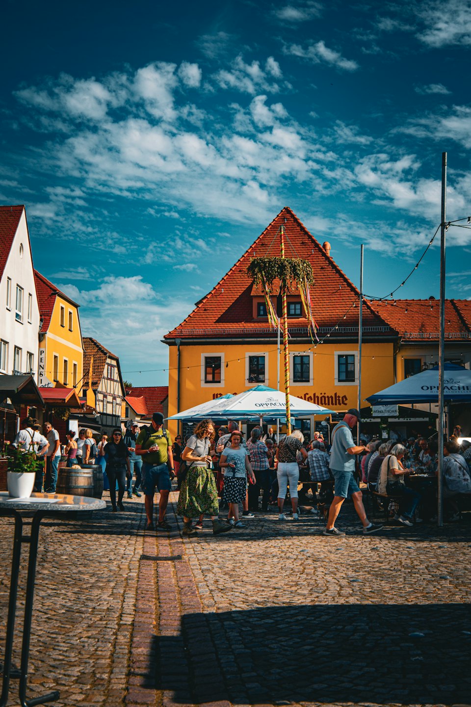Folk samles rundt en pyntet maistang på en torgplass.